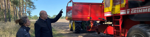 Annette Brockmann und Roger Lewandowski stehen vor einer Landwirtschaftsmaschine.