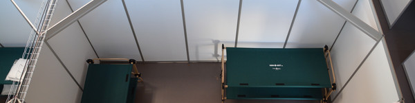 Blick von oben in eine Kabine des Willkommenszentrums: Zu sehen sind zwei Doppelstockbetten, ein Tisch und vier Stühle.