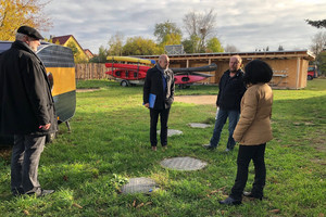 Vier Personen stehen in einigem Abstand auf einem Hof und unterhalten sich.