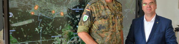 Zwei Personen stehen vor einem großen Bildschirm, der eine Landkarte anzeigt - Klick öffnet Bildbetrachter