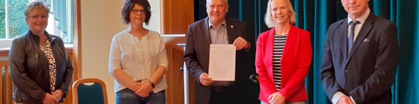 Fünf Personen stehen nebeneinander und schauen in die Kamera.