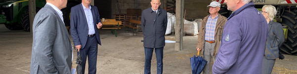 Eine Gruppe von Menschen steht im Kreis in einer Scheune.