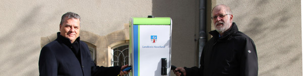 Dr. Jens Horn und Dr. Henning Kellner tanken Strom an der neuen E-Ladesäule vor dem Kreishaus in Nauen.