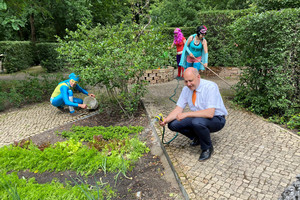 Landrat Roger Lewandowski gießt Blumen im Stinknormalen Stadtgarten von Rathenow.