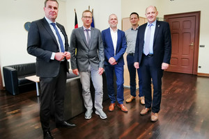 Fünf Männer stehen in einem Büro nebeneinander und schauen in die Kamera.