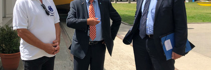 Drei Männer stehen auf dem Vereinsgelände und unterhalten sich.