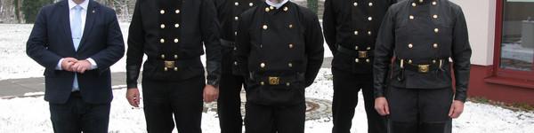 Sechs Männer, darunter fünf Schornsteinfeger stehen in einer Gruppe und schauen in die Kamera.