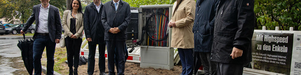 Eine Gruppe von Menschen steht vor einem Glasfaser-Schaltkasten.