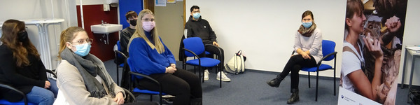 Eine Gruppe von Schülern sintzt mit der Referentin in einem Klassenraum.