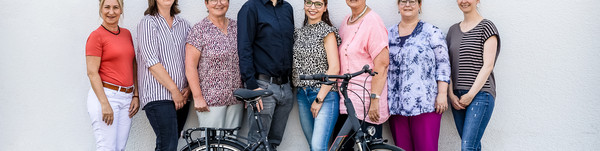 Acht Personen stehen vor einer Wand, davor steht ein Fahrrad - Klick öffnet Bildbetrachter