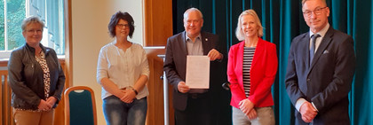 Fünf Personen stehen nebeneinander und schauen in die Kamera.