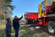 Annette Brockmann und Roger Lewandowski stehen vor einer Landwirtschaftsmaschine.