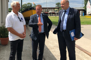 Drei Männer stehen auf dem Vereinsgelände und unterhalten sich.