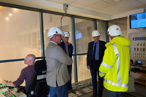 Vier Männer stehen im Kreis, im Hintergrund ist die Müllverbrennungsanlage zu sehen.