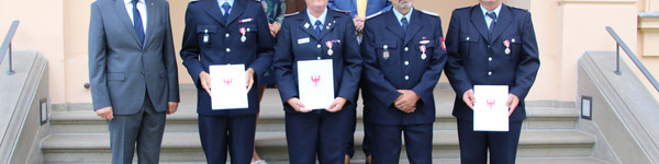 Die ausgezeichneten Feuerwehrleute stehen mit dem Landrat und zwei weiteren Personen auf einer Treppe.