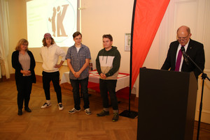 Der Landrat steht am Rednerpult und hält eine Laudatio. Daneben stehen die Preisträger.