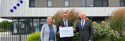 Drei Personen stehen vor dem Havelbus-Betriebshof und halten einen symbolischen Antrag in die Kamera - Klick öffnet Bildbetrachter.