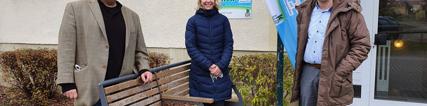 Drei Personen stehen vor dem Wohnblock, in dem sich die Musterwohnung befindet.