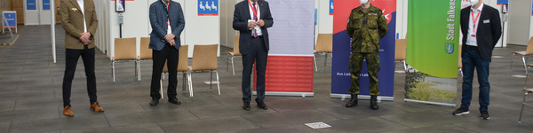 Fünf Personen stehen mit Abstand nebeneinander im Impfzentrum. Der Landrat steht in der Mitte und spricht.