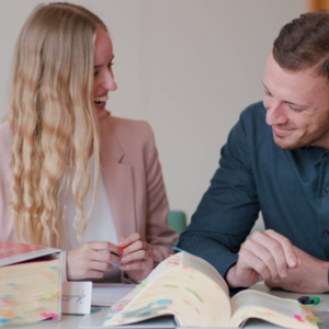 Zwei junge Menschen sitzen an einem Tisch und lernen gemeinsam