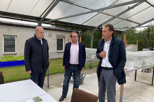 Drei Männer stehen im Halbkreis und unterhalten sich.