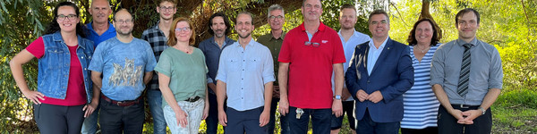 Eine Gruppe von Menschen steht unter einem Baum - Klick öffnet Bildbetrachter