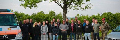 Eine Gruppe von Menschen steht zwischen zwei Autos.