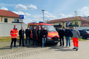 Einige Feuerwehrleute stehen auf einem Parkplatz vor einem Feuerwehrfahrzeug.