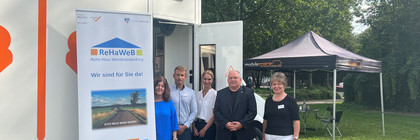 Fünf Personen stehen vor dem Beratungsmobil, im Hintergrund steht ein Pavillon mit Sitzmöglichkeiten - Klick öffnet Bildbetrachter