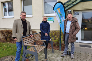 Drei Personen stehen vor dem Wohnblock, in dem sich die Musterwohnung befindet.