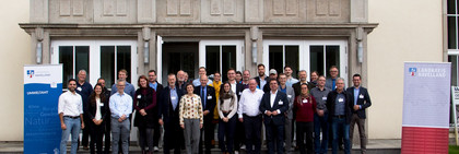 Klick öffnet Text, eine Gruppe von mehr als 30 Menschen vor einem Gebäude