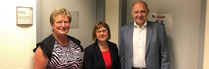 Drei Personen stehen in einem Flur vor einer Bürotür - Klich öffnet Bildbetrachter