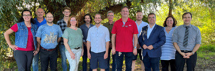 Eine Gruppe von Menschen steht unter einem Baum - Klick öffnet Bildbetrachter