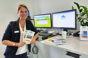 Eine Frau steht am Schreibtisch und hält Flyer in den Händen.