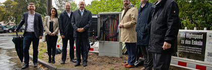 Eine Gruppe von Menschen steht vor einem Glasfaser-Schaltkasten.