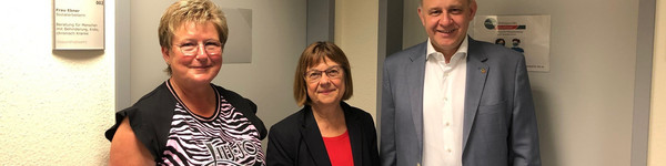 Drei Personen stehen in einem Flur vor einer Bürotür - Klich öffnet Bildbetrachter