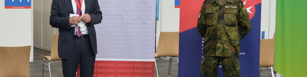 Zwei Männer stehen nebeneinander vor einem Aufsteller mit der Aufschrift "Landkreis Havelland".