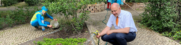 Landrat Roger Lewandowski gießt Blumen im Stinknormalen Stadtgarten von Rathenow.