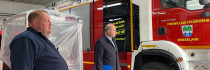 Zwei Männer stehen neben einem Feuerwehrauto.