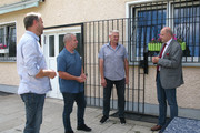 Landrat Lewandowski unterhält sich mit drei Mitgliedern des ESV Lok Elstal vor einem Vereinsgebäude.