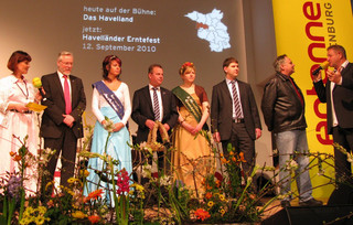 Kurz vor der Übergabe der Erntekrone auf der Antenne Brandenburg-Bühne v.l.: Moderatorin Marina Ringel, Landrat Dr. Burkhard Schröder, Ketziner Fischerkönigin Jennifer Kiesewalter, Ketziner Bürgermeister Bernd Lück, 2. Havelländer Erntekönigen Mandy Hinze, Friesacks Amtsdirektor Christian Pust, Geschäftsführer des MAFZ-Erlebnispark-Paaren, Gerhard Weiß, und Moderator Carsten Gohlke.